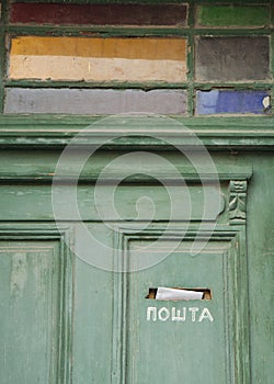 Green wooden door with stained glass on traditional house