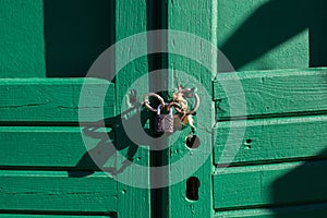 Green wooden doors locked with padlocks.