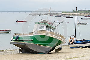 Green wooden fishing boat moored on the shore