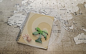 Green wooden palm tree and red turtle with sea shell on notebook on world map