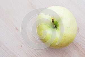 Green or yellow apple in wooden plate.