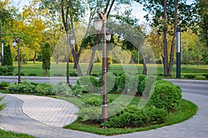 Green-yellow autumn park with clipped bushes and low lanterns