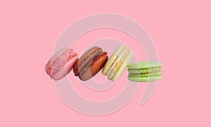 Green, yellow, brown and pink macarons isolated on a pink background. without a shadow