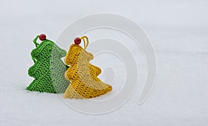 Green and yellow knitted toy on white snow