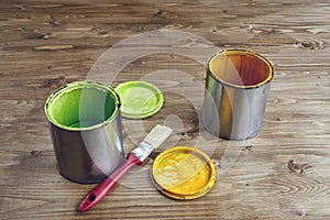 Close-up of colored paint can and brush on wooden background