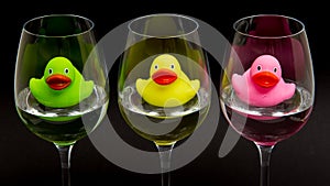Green, yellow and pink rubber ducks in wineglasses