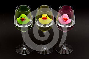 Green, yellow and pink rubber ducks in wineglasses