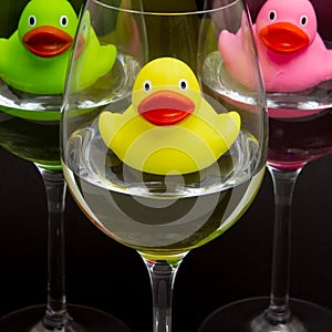 Green, yellow and pink rubber ducks in wineglasses