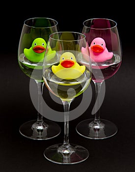 Green, yellow and pink rubber ducks in wineglasses