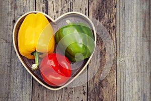 Green, yellow and red bell pepper over rustic textured wooden background. Healthy vegetables, food.