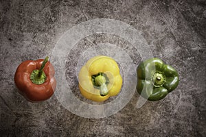 Green, yellow  and Red Bell Peppers on a black cement Background