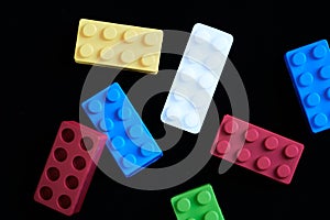 Colorful construction bricks with a paracetamol tablet on a black background photo