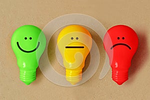 Green, yellow and red light bulb with different facial expressions