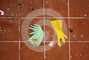 Green and yellow rubber kitchen gloves on the ground.