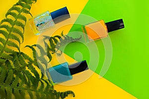 Green and yellow, shiny nail Polish lie on a yellow background