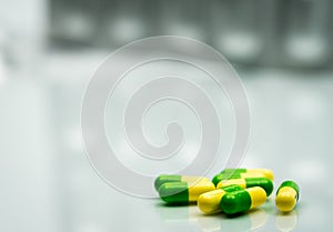 Green, yellow tramadol capsule pills on blurred silver blister p