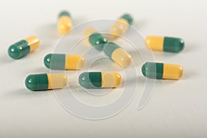 Green, yellow tramadol capsule pills on white background.Pain killer capsules called