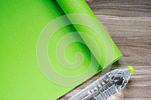 Green yoga mat on a wooden background with water bottle, Top Vie