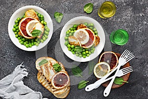 Green young peas, cheese haloumi, lemon. orange salad with slices of bread. Top View