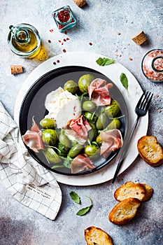 Green zebra tomatoes and sliced burrata cheese salad with fresh arugula, prosciutto or jamon, olives and toasted bread.