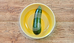 Green zucchini squash with patterned skin on a yellow plate on a wooden tabletop