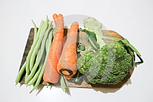 Greenbeans, carrots and broccoli on the wooden board