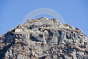 Greened cliff under a blue sky