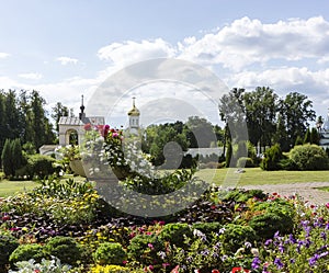 Greenery floral historical monastery garden with colorful spring summer flowers, trees and old church buildings