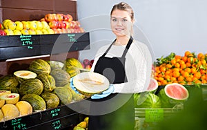 Greengrocery salesgirl offering melon
