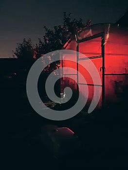 Greenhouse at night and the red light of the street lamp