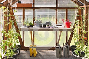 Greenhouse with a table full of gardening tools. Hobbies and relaxation concept