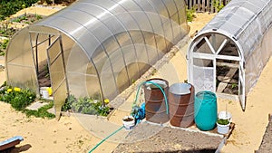 Greenhouses and barrels of water for watering in the garden