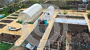 Greenhouses among vegetable ridges in the garden, top view