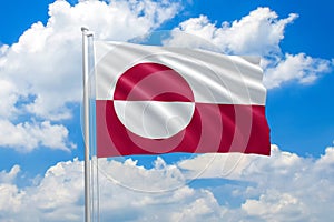 Greenland national flag waving in the wind on clouds sky. High quality fabric. International relations concept