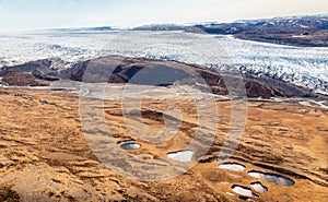 Greenlandic ice sheet melting glacier into river with tundra aerial view, near Kangerlussuaq, Greenland