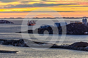 Greenlandic sunset landscape with cargo ship sailing away in Nuuk fjord, Greenland