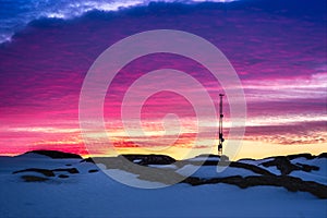 Greenlandic sunset sky with antenna and rocks with snow in the f