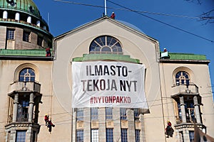 Greenpeace activists place Climate action now banner in Finnish on the wall of the New Student House.