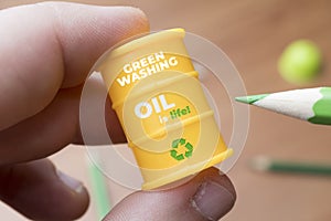Greenwashing concept. Man paints a barrel of oil with a green pencil. Greenwashing is a communication technique aimed at building