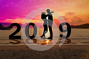 Greeting card 2019 happy new years. Silhouette young couple embrace each other with sunset at tropical beach. People