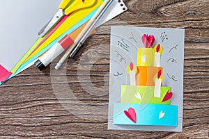 Greeting card with birthday cake congratulation on a wooden table.
