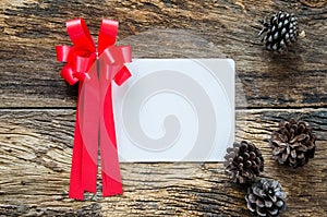 Greeting card for christmas with red ribbon and fir on wooden ta