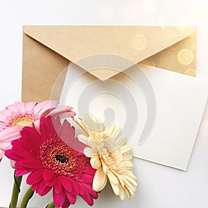 Greeting card concept with envelope and gerbera flower. Blank paper postcard, vintage envelope and gerbera flowers