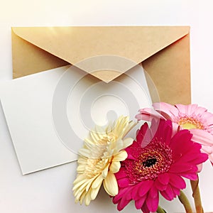 Greeting card concept with envelope and gerbera flower. Blank paper postcard, vintage envelope and gerbera flowers
