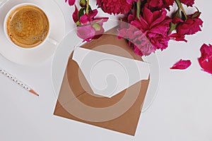 Greeting card in the envelope, flat lay with coffee and pink peonies, mockup