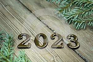 Greeting card happy new year 2023 on a background of white boards with a branch of a Christmas tree with bright lights