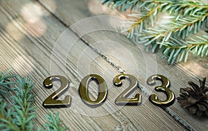 Greeting card happy new year 2023 on a background of white boards with a branch of a Christmas tree with bright lights