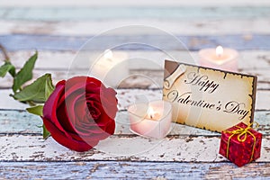 Greeting card with Happy Valentine`s Day text, red rose, gift box, and candles