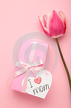 Greeting card with inscription i love mom. Gift box with flowers and gard on pink background. Vertical photo