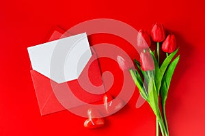 Greeting card with love. Red envelope with blank paper, bouquet of tulips and heart shaped candles